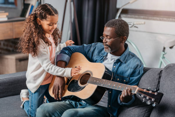 istock man playing guitar with daughter at home 834335100