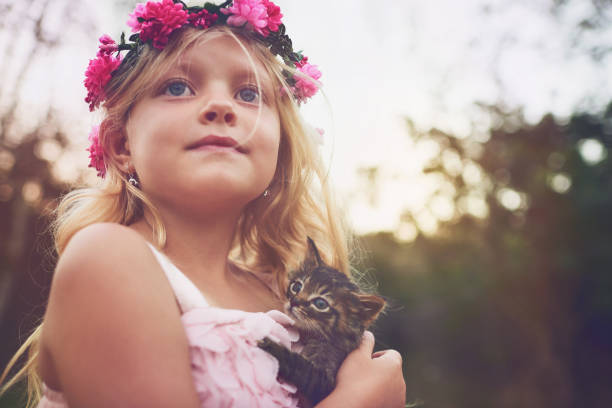 Shot of a little girl holding a kitten and looking into the distance while standing outside in nature