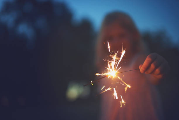 Sparkles are cool Shot of a unrecognizable little girl playing with a sparkler at night time outside in nature dark pink dress stock pictures, royalty-free photos & images