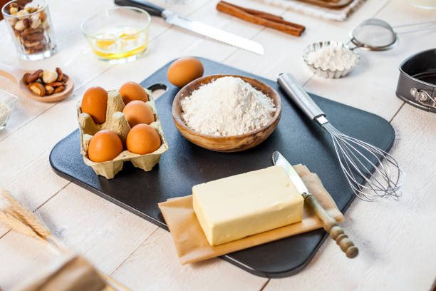 istock Baking ingredients in rural kitchen - dough recipe ingredients (eggs, flour, milk, butter, sugar) and rolling pin on wooden white table. 834338628