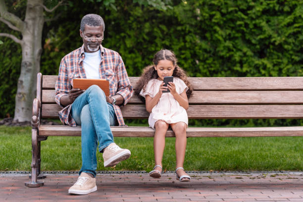 girl and her grandfather using smartphone and digital tablet