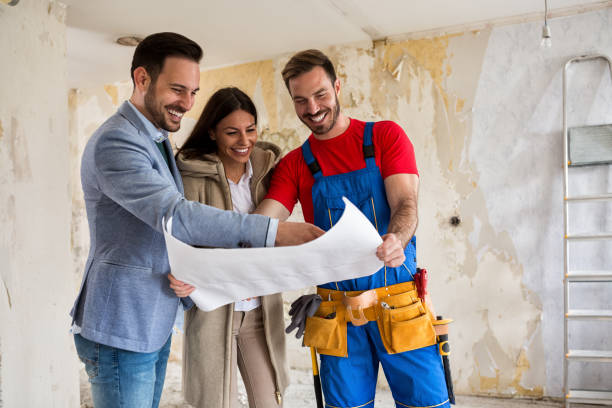istock Beutiful young couple looking blueprints of their home with handyman 834345472