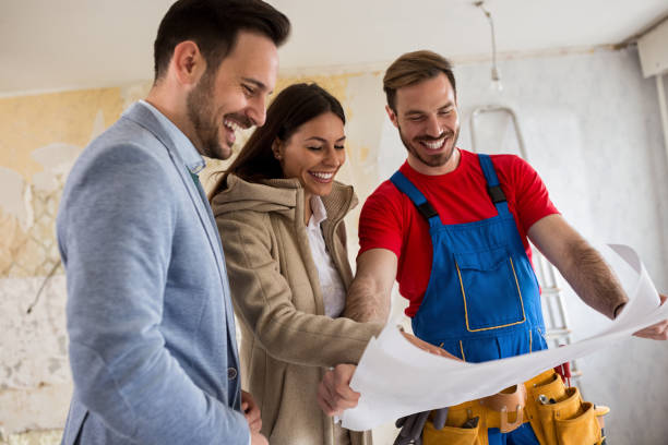istock Beutiful young couple looking blueprints of their home with handyman 834346046