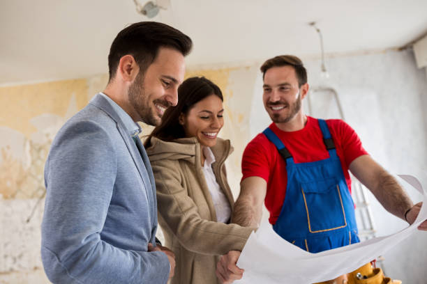 istock Beutiful young couple looking blueprints of their home with handyman 834349912