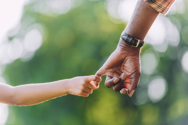 blick auf afroamerikanische großvater hand in hand mit kleinen enkelin beschnitten - touching children only day europe stock-fotos und bilder