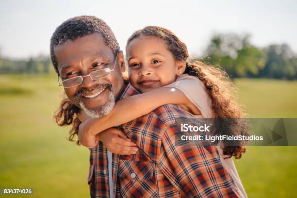 Granddaughter Hugging Her Smiling Grandfather On Green Lawn Stock Photo - Download Image Now