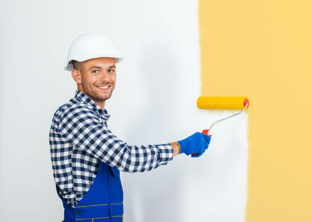 istock Smiling handsome painter painting the wall in beige 834376128