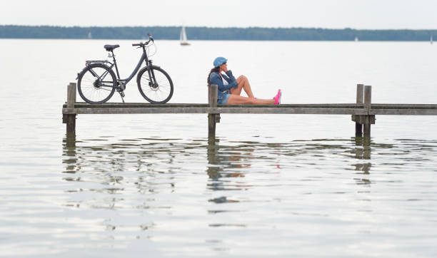 femme avec vélo assis sur la jetée pour se détendre - steinhuder meer photos et images de collection