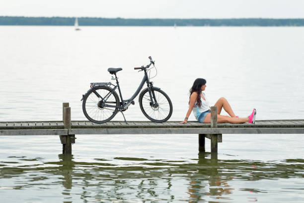 femme avec vélo assis sur la jetée pour se détendre - steinhuder meer photos et images de collection