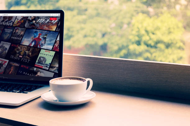 netflix ウェブサイト画面の macbook pro のカフェでノート パソコンに表示。netflix は、国際的に普及しています。 - home movie ストックフォトと画像