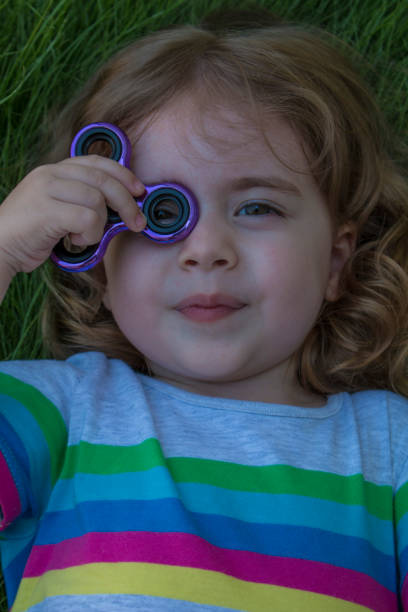 istock Little beautiful girl is playing blue spinner in hand. 834408528