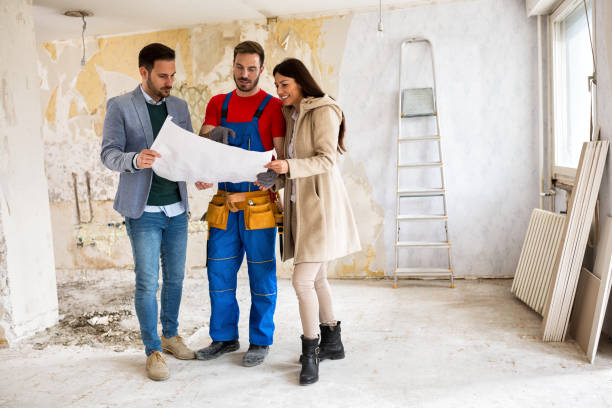 istock Beutiful young couple looking blueprints of their home with handyman 834420300