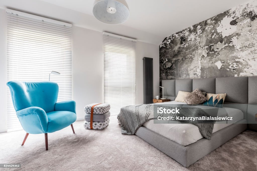 Bedroom with vintage blue armchair Monochromatic gray bedroom with grunge wall, wooden bedside table, white walls and blue vintage style armchair Carpet - Decor Stock Photo