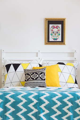 Scandinavian white bed with colorful pillows and mixed patterns