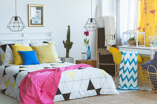 Colorful bedroom with yellow armchair and glass terrarium with cactus