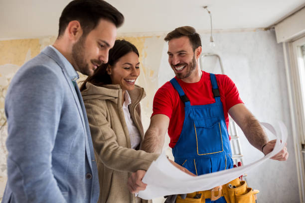istock Beutiful young couple looking blueprints of their home with handyman 834448104