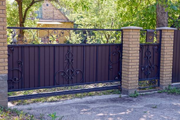 istock Brown iron gate with a pattern and a brick fence in front of the road 834468488