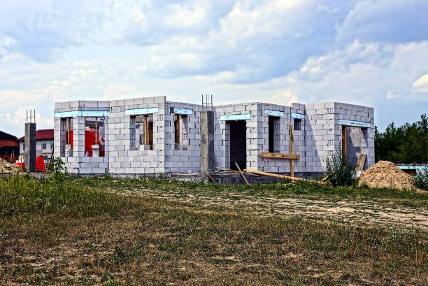 istock Construction of a white brick house in the grass against the sky 834512136