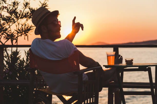 istock Young man enjoying sunset at a beach bar 834565662
