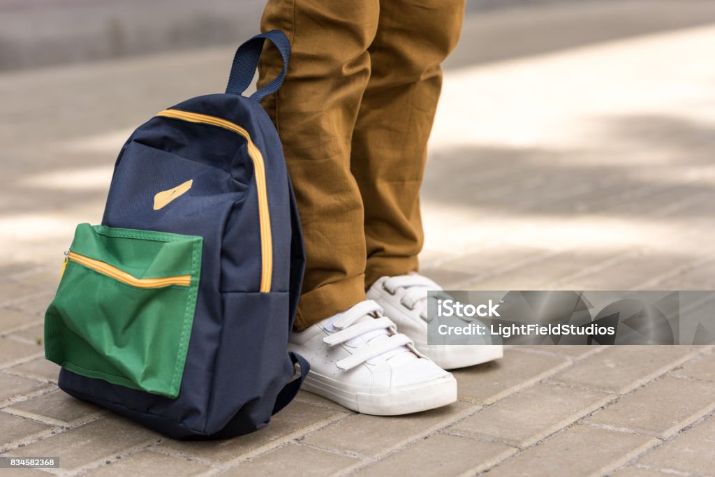 路上のバックパックと立っているスタイリッシュな男子生徒のクロップ撮影 - バックパックのロイヤリティフリーストックフォト
