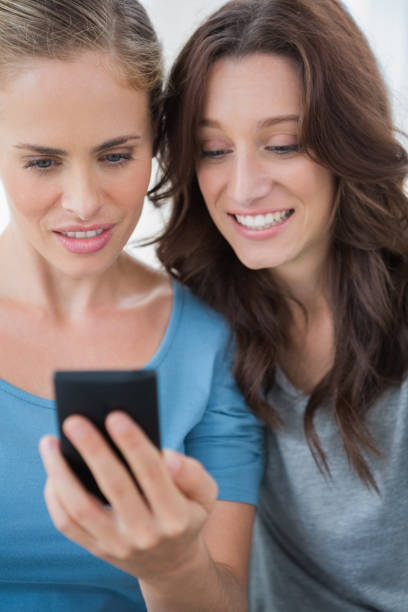 istock Smiling friends looking at mobile phone 834589740