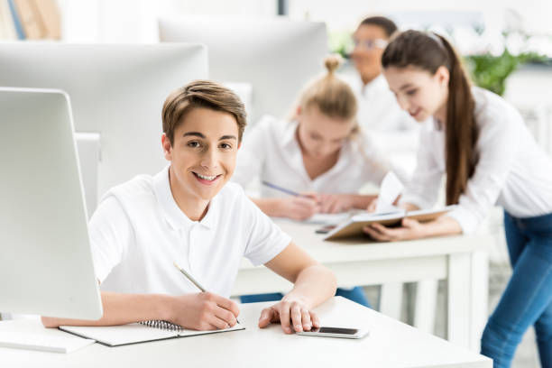 istock portrait of smiling student looking at camera while sitting at table during lesson in classroom 834600628
