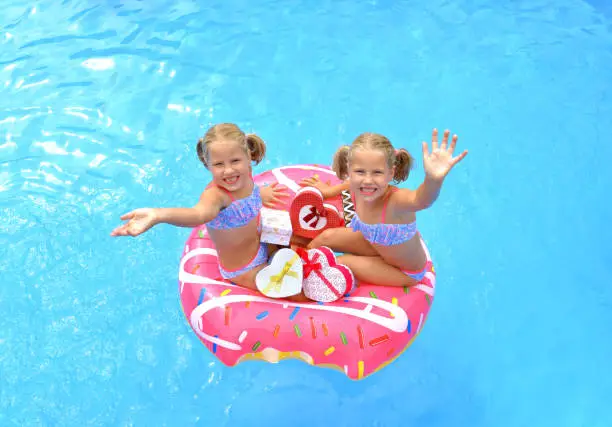 Twin sisters at Christmas sit in a swim ring in the swimming pool and fill 