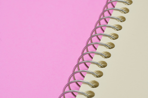 Spin notebook made of wire, coil Pink background. copy space.