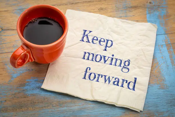Keep moving forward reminder or advice - handwriting on a napkin with a cup of espresso coffee