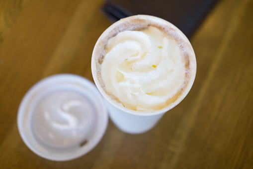 Hot coffee with wipped cream in a paper cup, close up