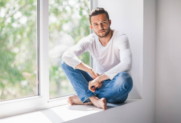 istock Handsome man relaxing on window sill in lotus pose 834652848