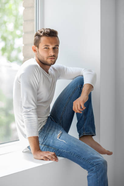 istock Handsome thoughtful man relaxing on window sill 834652958