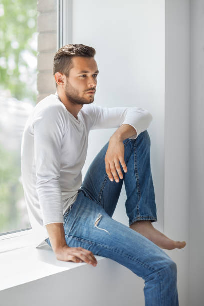 istock Handsome thoughtful man relaxing on window sill 834652962
