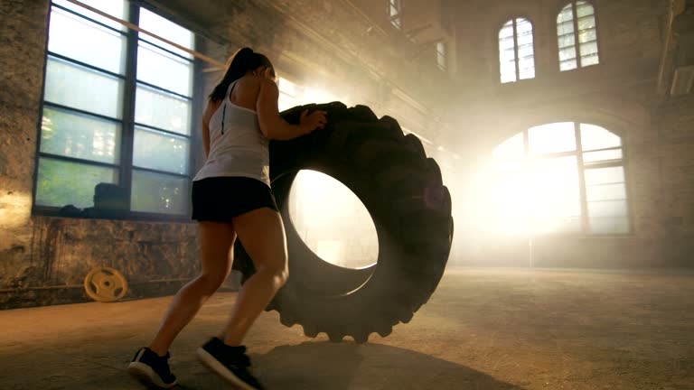 Fit Athletic Woman Lifts Tire as Part of Her Cross Fitness/ Bodybuilding Training.