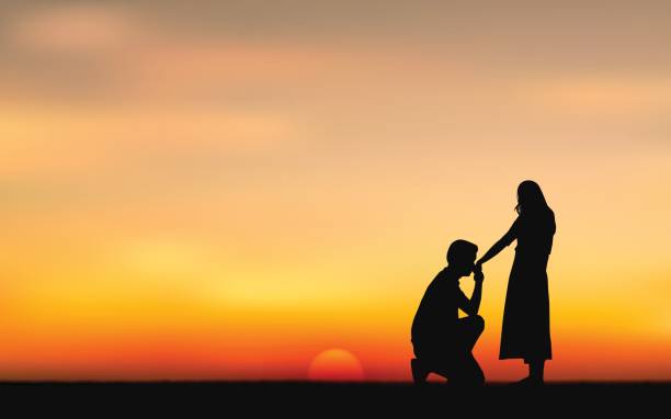 istock Silhouette couple man down on one knee proposing to woman under sunset sky background 834704022