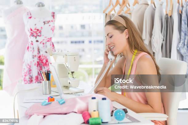 Young Female Fashion Designer Using Phone In Studio Stock Photo - Download Image Now