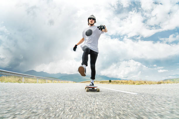istock A guy in a helmet and sunglasses accelerates pushing his foot on his longboard 834722566