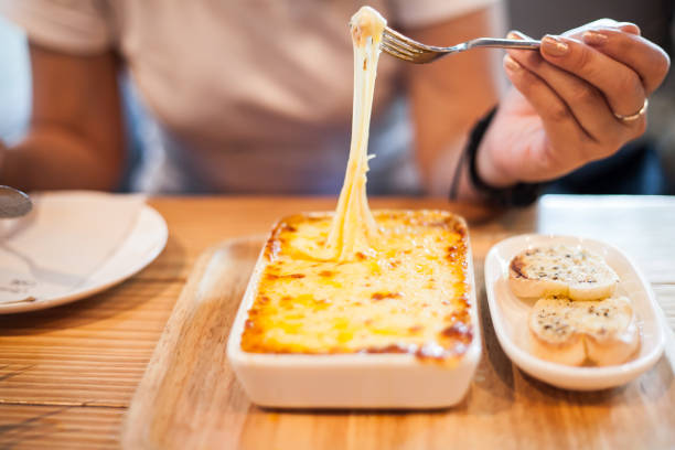 woman eating a delicious lasagna - mozzarella cheese italy tomato imagens e fotografias de stock