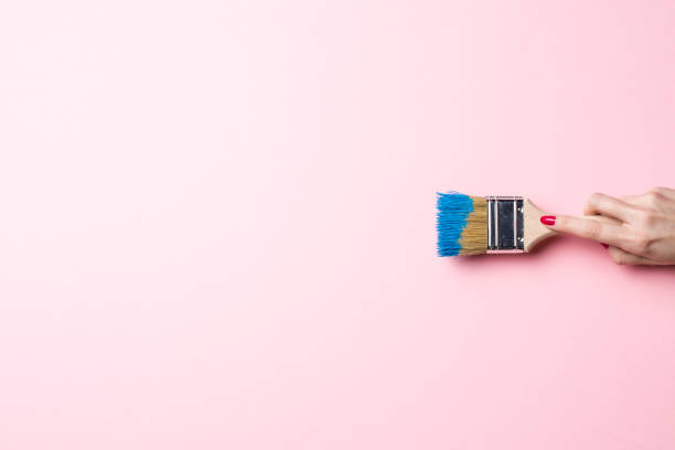 Woman painting empty pink wall