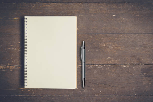 istock Top view notebook and pen on wood table with space, Vintage filter. 834730502