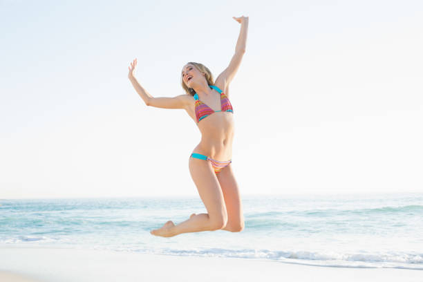 istock Beautiful blonde young woman jumping on beach 834735936