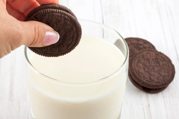Close up of a woman dunking chocolate cookies in milk