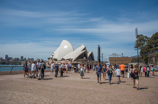 Sydney,NSW,Australia-November 20,2016: Tourists walking to the Sydney Opera House at Bennelong Point with waterfront architecture in Sydney, Australia.