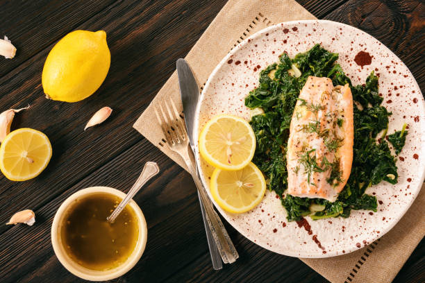 Baked salmon served on stewed spinach with lemon butter sauce. stock photo