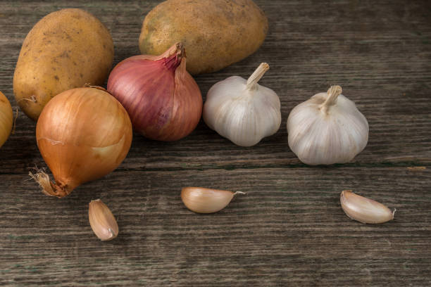 istock Garlic, onion and potatoes on an old table 834762850
