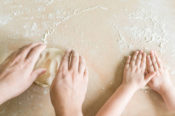 Children's and dad's hands makes raw dough