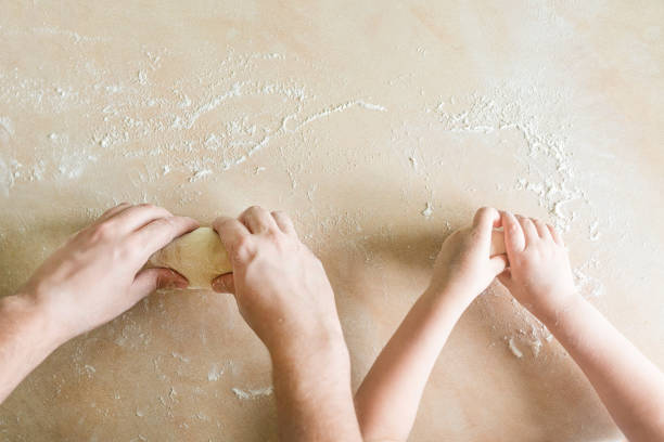 Children's and dad's hands makes raw dough
