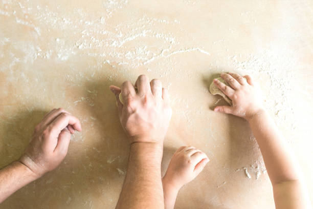 Children's and dad's hands makes raw dough