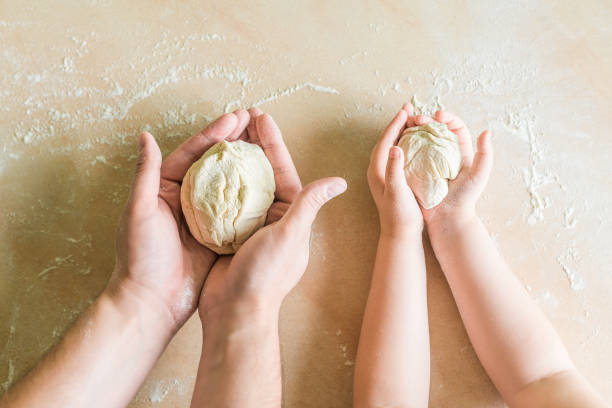 Children's and dad's hands makes raw dough