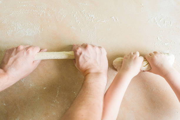 Children's and dad's hands makes raw dough